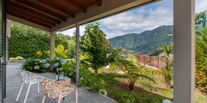 The Outstading Views Of The Surrounding Countryside And Mountais From Casa Hortensia By Ourmadeira With A Table For Two And Some Wine Glasses