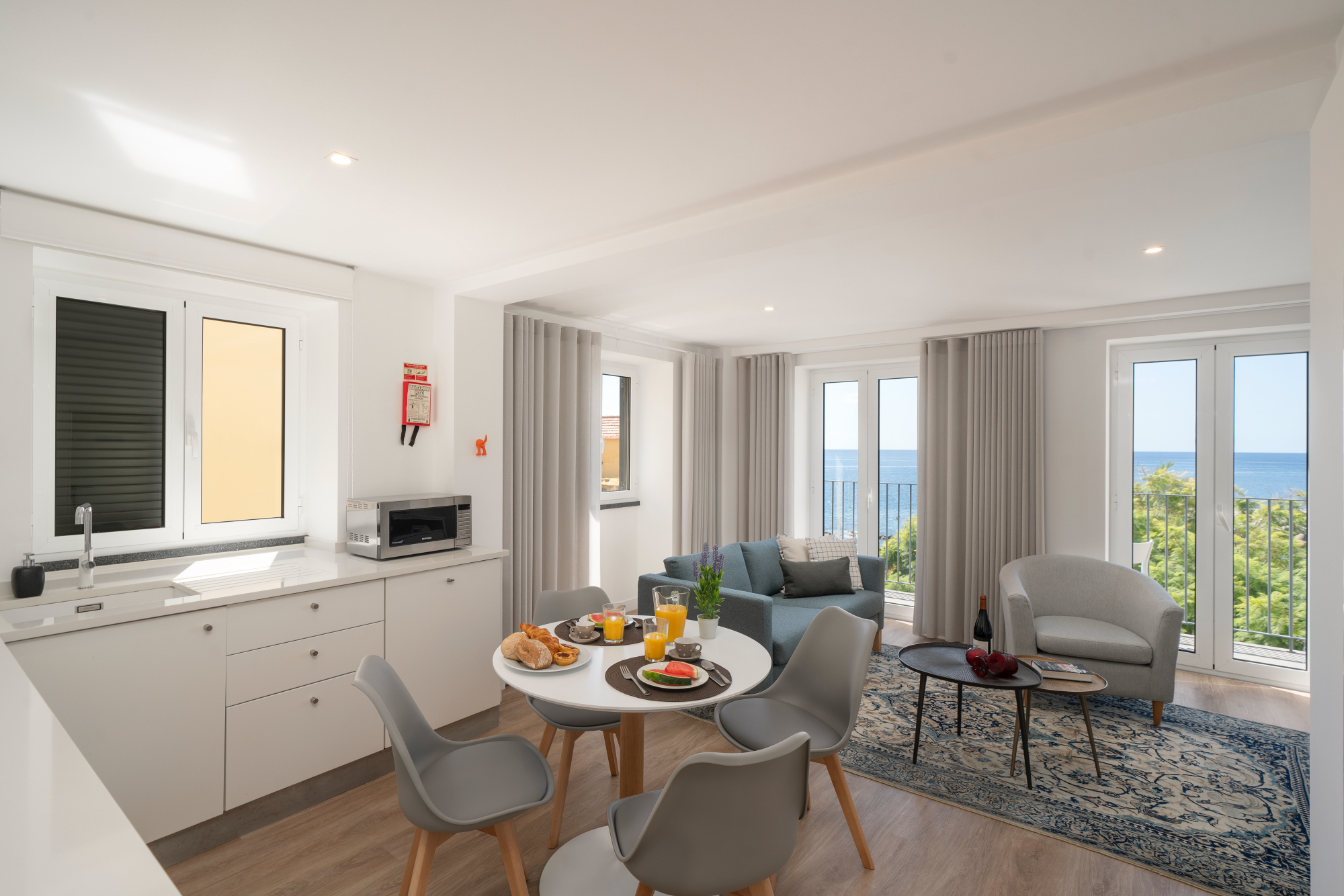 Open Concept Kitchen And Living Room With Panoramic Windows Revealing A Breathtaking View Of The Ocean By The Fort Of Old Town Apartments
