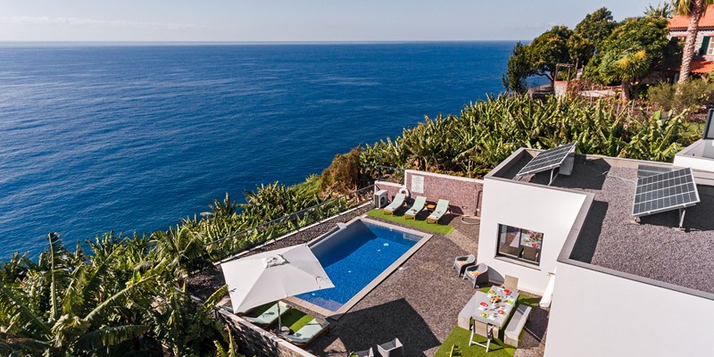 Aerial Side View Of Graycis House By Ourmadeira Revealing The Architectural Design Swimming Pool Area Surrounding Banana Groves And The Ocean Stretching Out In The Background