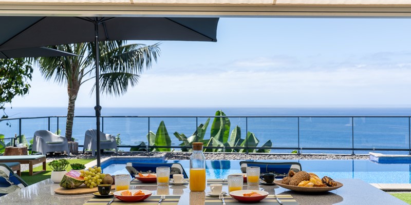 Outdoor Breakfast Setup By The Pool At Graycis House By Ourmadeira With Ocean Views On The Horizon And A Serene Coastal Atmosphere