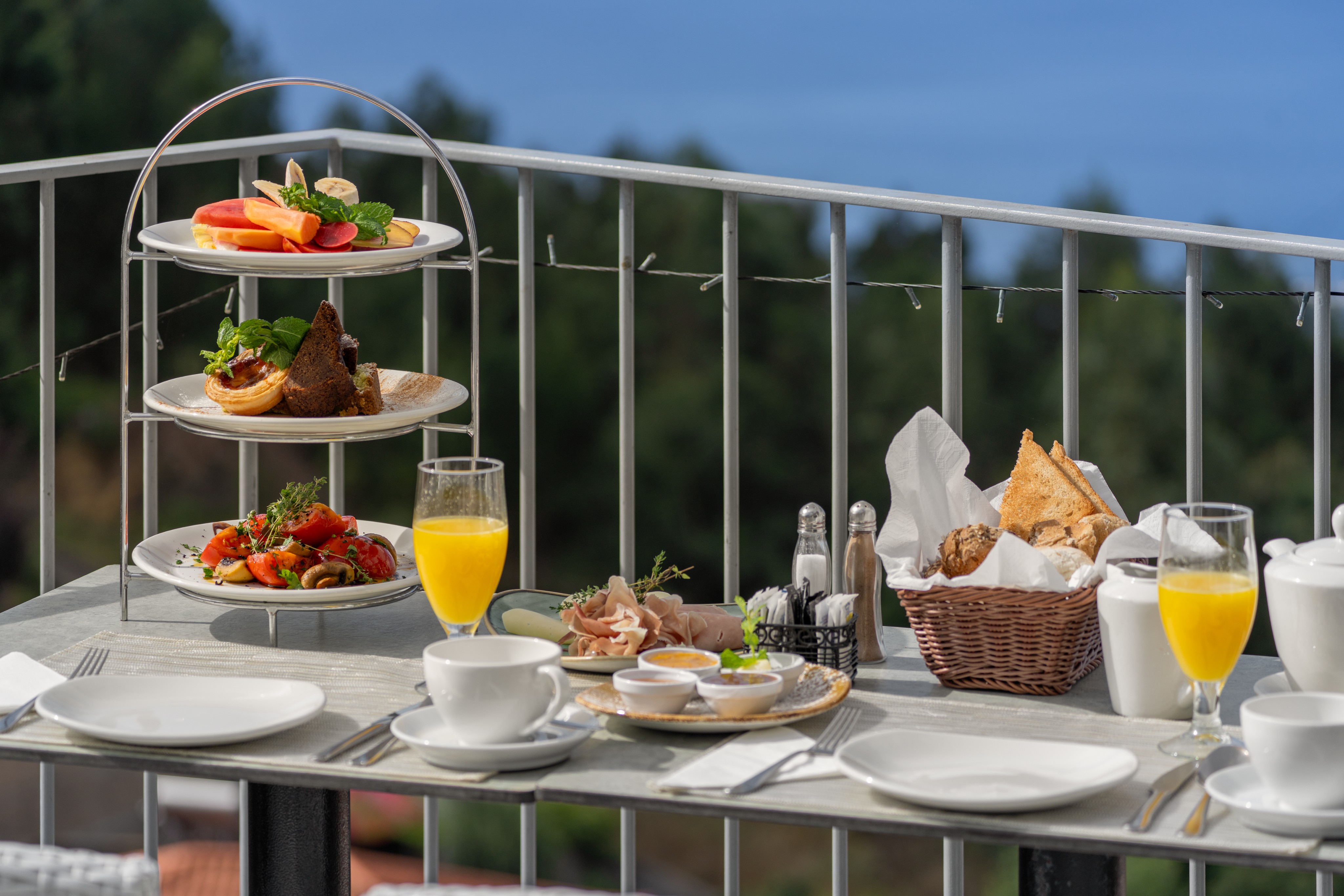 Close Up Of A Breakfast Table Outdoors At Babosas Village By Ourmadeira Featuring Fresh Fruit Pastries And Coffee With Scenic Views Of Madeira In The Background