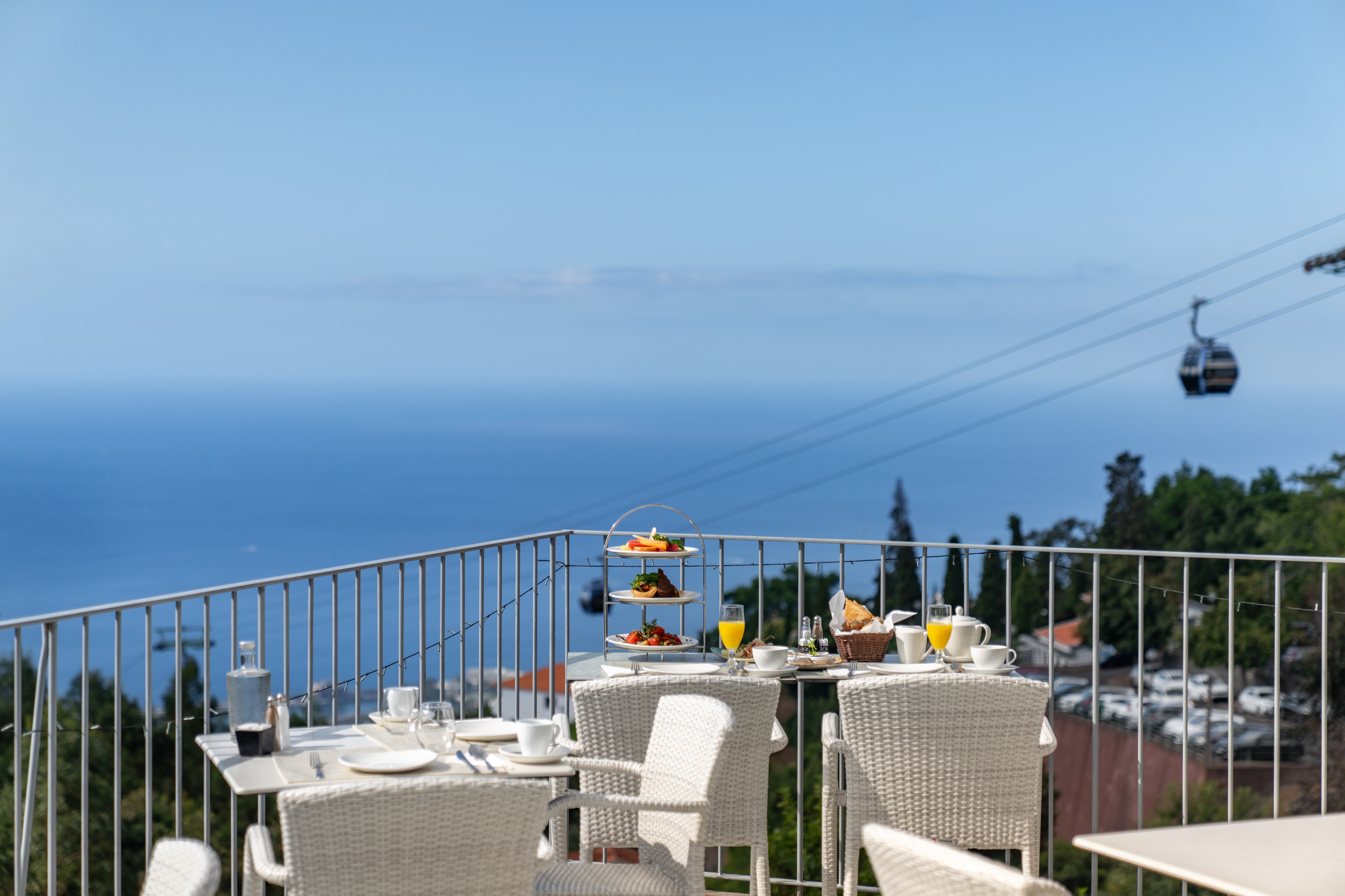 Outdoor Breakfast Setup On The Terrace At Babosas Village By Ourmadeira With Stunning Views Of The Sea And Madeira Cable Car In The Background Offering A Peaceful And Scenic Dining Experience