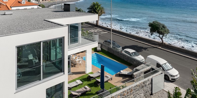 The Modern Villa With Minimalist Architecture And Large Glass Windows Overlooking The Ocean At Beachfront By Ourmadeira